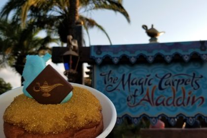 The "Wish Granted Donut" in front of "The Magic Carpets of Aladdin" ride sign at Walt Disney World.
