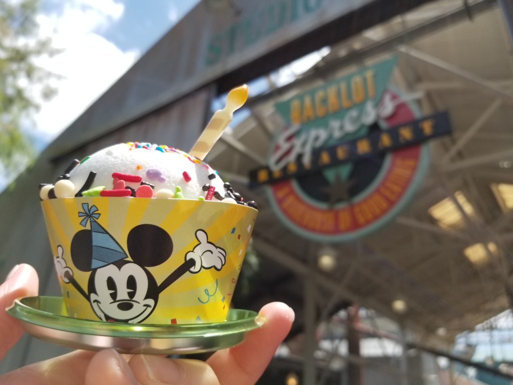 The Mickey Celebration Cake in front of the sign for the Backlot Express in Disney's Hollywood Studios.