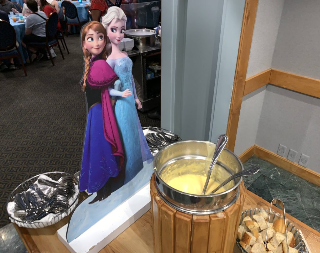 A Character cut-out of Anna and Elsa behind the Duke of Weselton’s Cheese Fondue at the Frozen Ever After Dessert Party