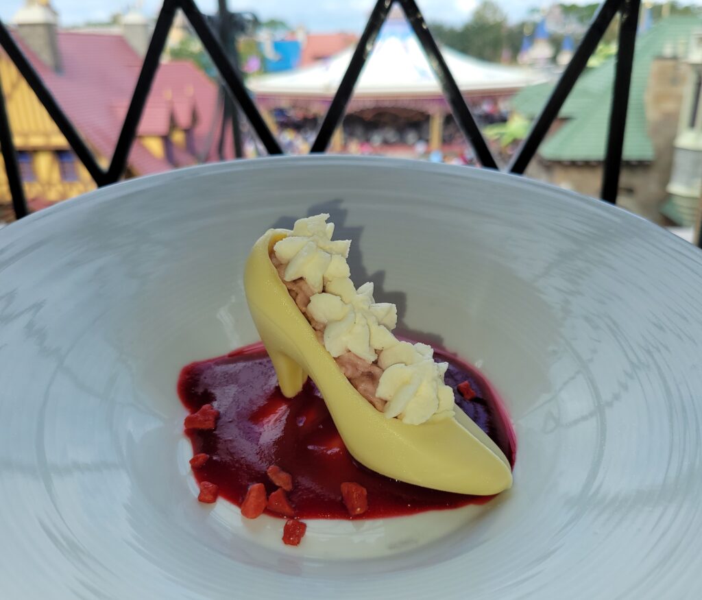 Picture of the inside contents of the Lost Slipper Dessert at Cinderella's Royal Table in the Magic Kingdom which features a mini-white chocolate slipper filled with raspberry mouse and whipped cream.