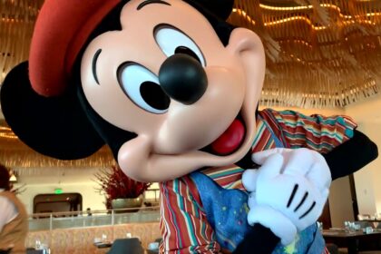 Mickey Mouse touching his heart in his artistic painting outfit at Topolino’s Terrace in Disney World