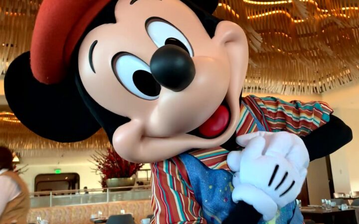Mickey Mouse touching his heart in his artistic painting outfit at Topolino’s Terrace in Disney World