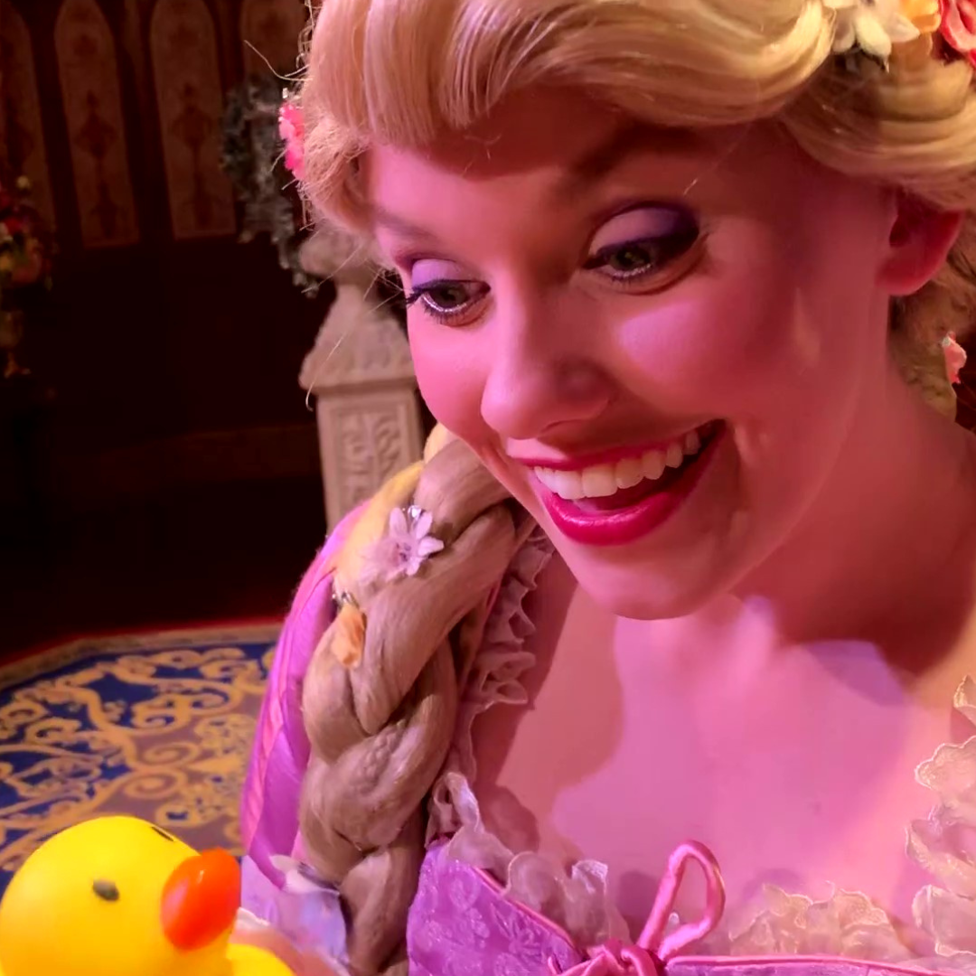 A picture of Rapunzel in a pink dress smiling at a rubber ducky (the Snuggly Duckling) in the Magic Kingdom in Walt Disney World